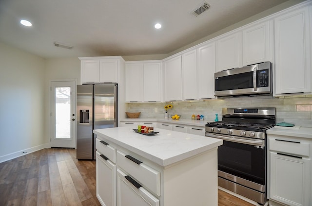 kitchen with a center island, white cabinets, stainless steel appliances, and wood-type flooring