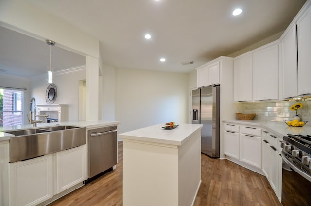 kitchen featuring appliances with stainless steel finishes, sink, pendant lighting, light hardwood / wood-style floors, and a kitchen island