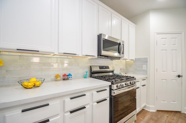 kitchen featuring appliances with stainless steel finishes, backsplash, light stone counters, white cabinets, and light hardwood / wood-style floors