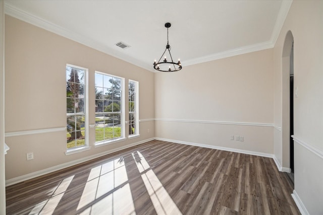 unfurnished dining area with dark hardwood / wood-style flooring, an inviting chandelier, and crown molding