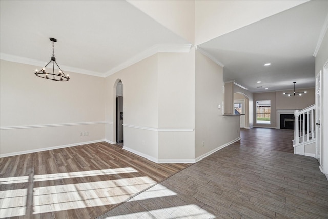 unfurnished room with dark hardwood / wood-style floors, ornamental molding, and an inviting chandelier