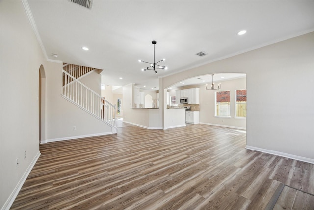 unfurnished living room with hardwood / wood-style floors, an inviting chandelier, and ornamental molding