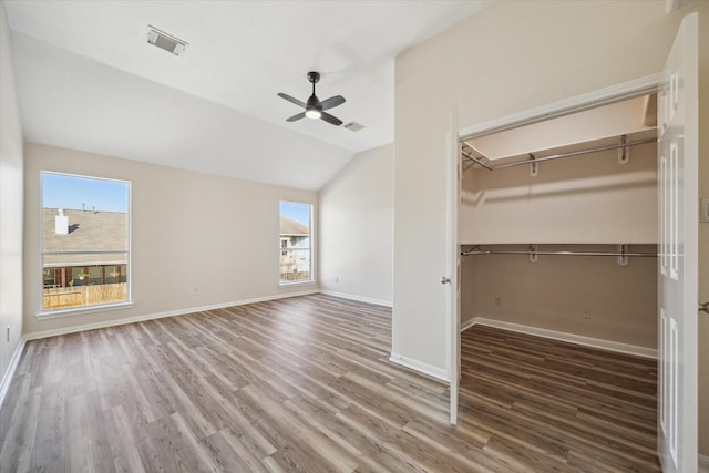 unfurnished bedroom with ceiling fan, a closet, dark hardwood / wood-style flooring, and vaulted ceiling