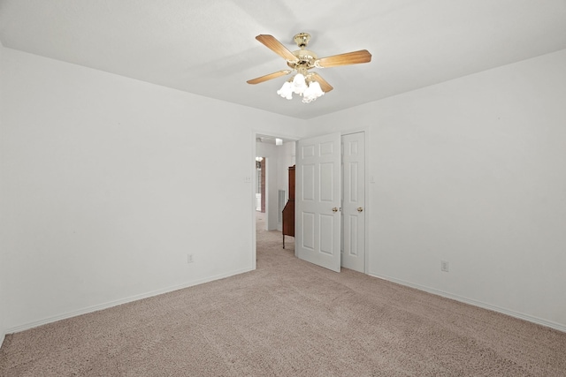 unfurnished room with a ceiling fan, baseboards, and light carpet