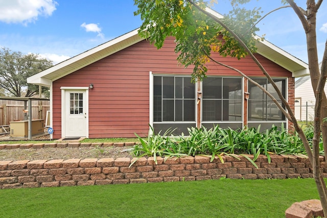 rear view of house featuring a lawn and fence