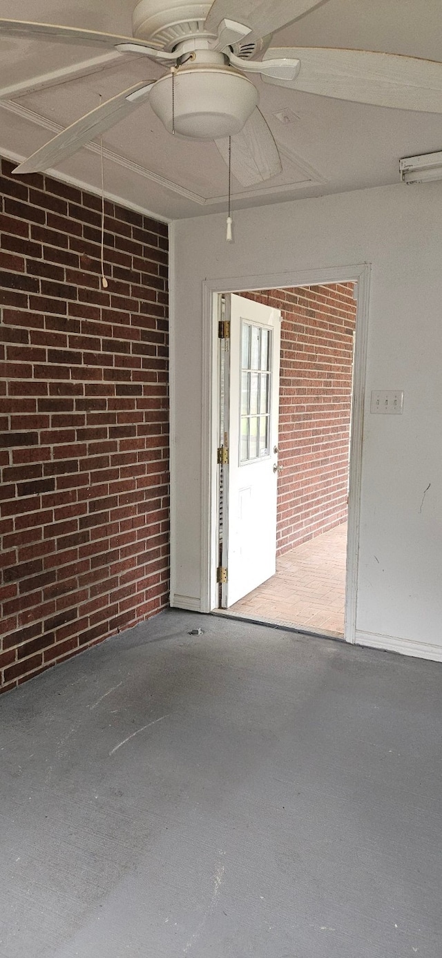 interior space featuring ceiling fan, brick wall, and concrete flooring