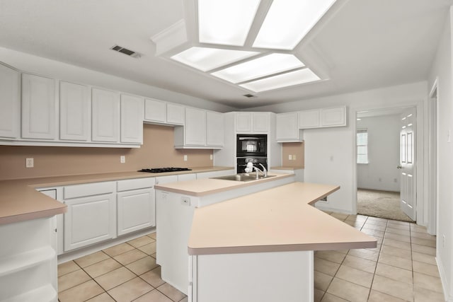 kitchen with black appliances, light tile patterned flooring, visible vents, and a sink
