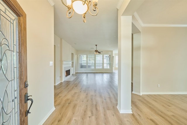 foyer entrance featuring light hardwood / wood-style floors, ornamental molding, and ceiling fan with notable chandelier