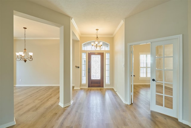 foyer featuring a notable chandelier, light wood-type flooring, french doors, and a wealth of natural light