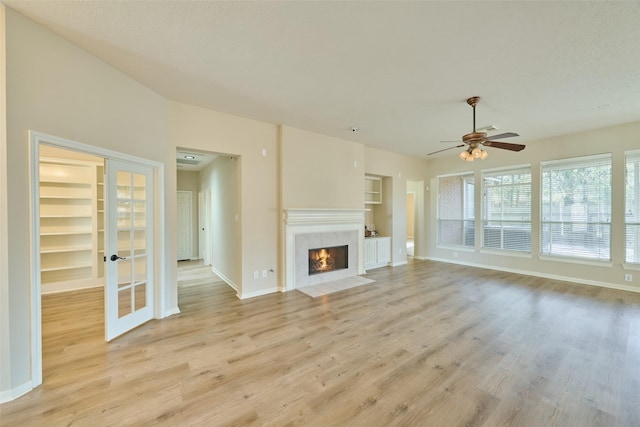 unfurnished living room featuring a textured ceiling, ceiling fan, light wood-type flooring, and built in features