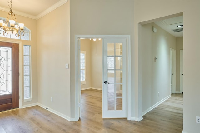 entrance foyer featuring a wealth of natural light, crown molding, a chandelier, and light hardwood / wood-style flooring