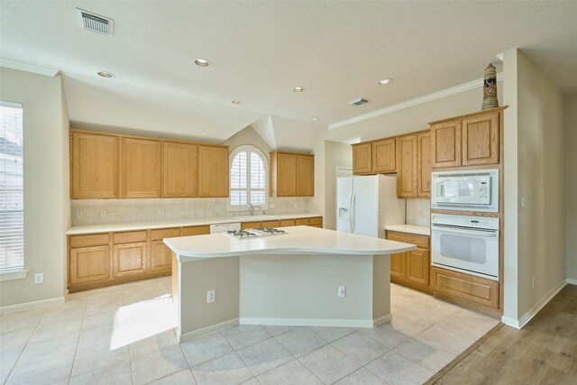 kitchen with white appliances, a center island, tasteful backsplash, and crown molding