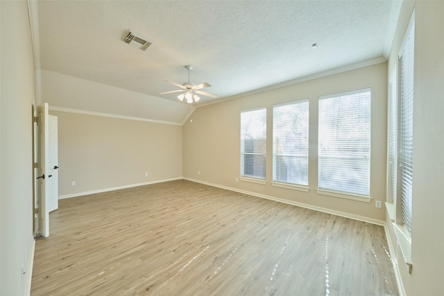 spare room with lofted ceiling, a textured ceiling, light wood-type flooring, and crown molding