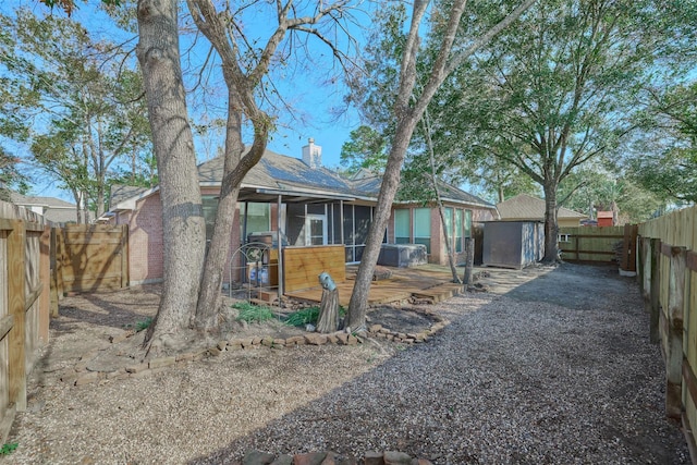 rear view of property featuring a sunroom and a storage shed