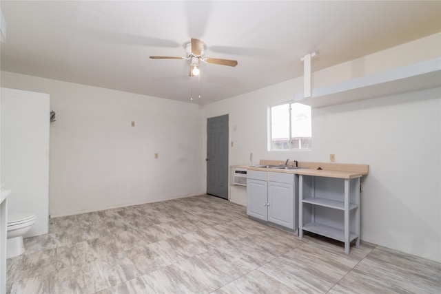 kitchen with an AC wall unit, gray cabinets, ceiling fan, and sink