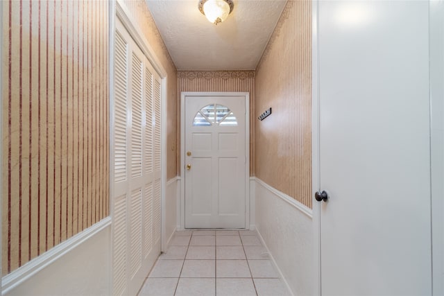 doorway featuring light tile patterned floors and a textured ceiling