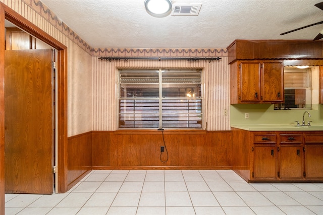 kitchen featuring a textured ceiling, ceiling fan, light tile patterned flooring, and sink