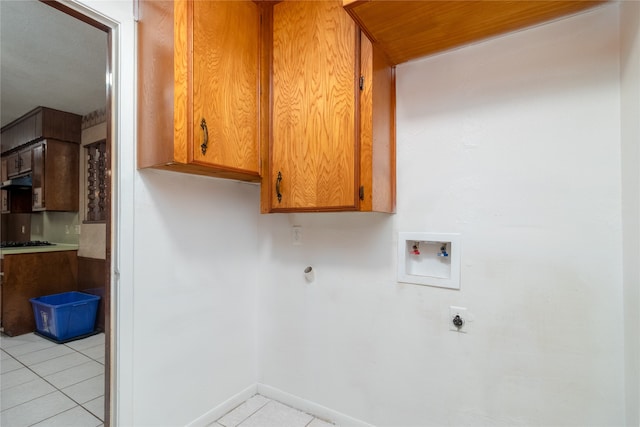 laundry room featuring electric dryer hookup, hookup for a washing machine, light tile patterned flooring, and cabinets