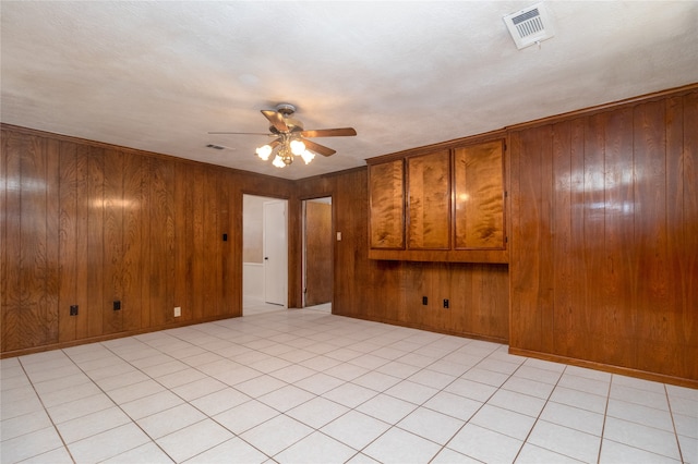 unfurnished room with ceiling fan, wood walls, and light tile patterned flooring