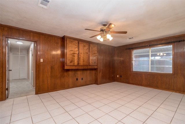 empty room featuring ceiling fan and wooden walls