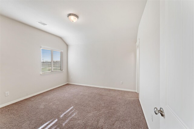 carpeted spare room featuring vaulted ceiling