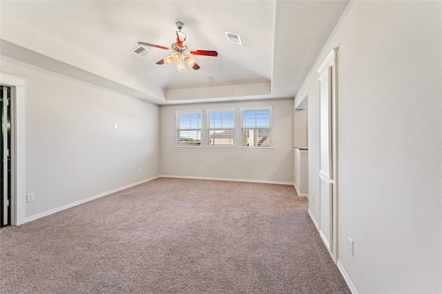 carpeted spare room featuring a raised ceiling and ceiling fan