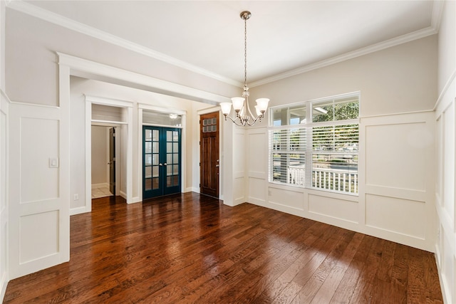 unfurnished dining area with a chandelier, french doors, crown molding, and dark wood-type flooring