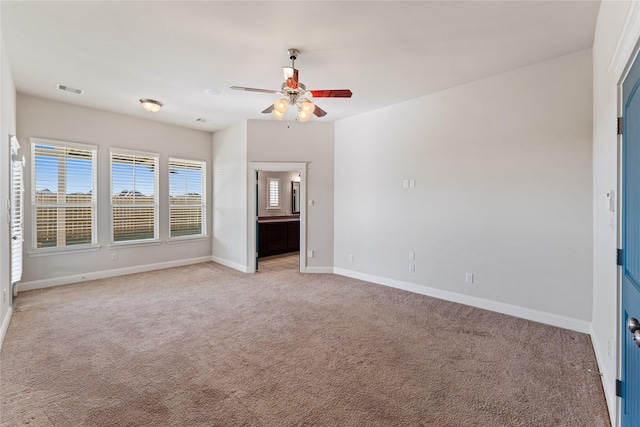 unfurnished bedroom featuring ceiling fan, light colored carpet, and ensuite bath