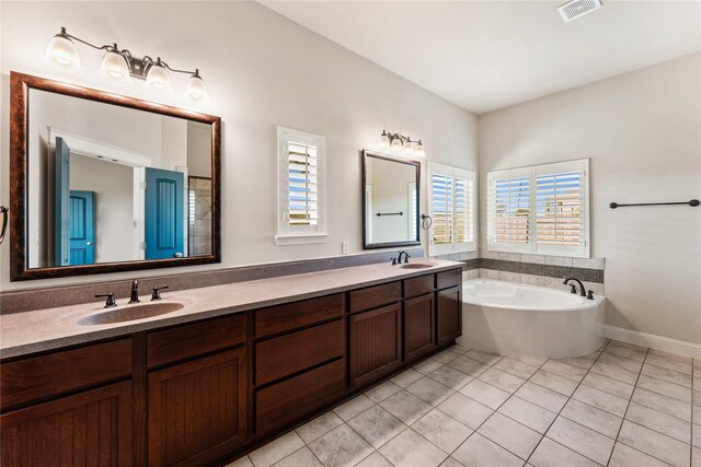 bathroom with tile patterned floors, a washtub, and vanity