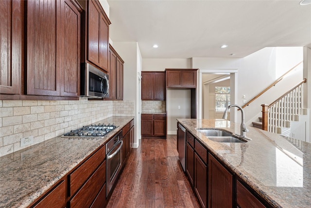 kitchen featuring light stone countertops, backsplash, stainless steel appliances, dark wood-type flooring, and sink