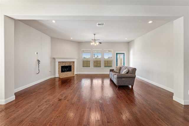 sitting room with a tile fireplace, ceiling fan, and dark wood-type flooring