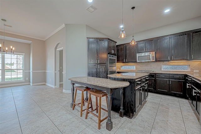 kitchen featuring a center island, hanging light fixtures, a breakfast bar area, ornamental molding, and stainless steel appliances