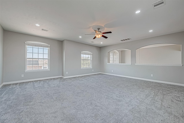 carpeted empty room with ceiling fan and a wealth of natural light