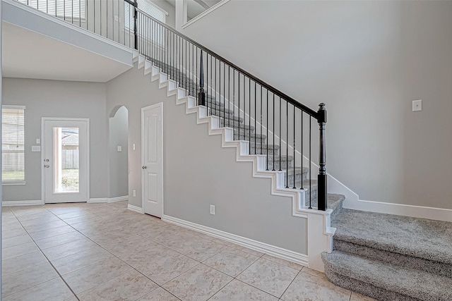 stairs with tile patterned flooring and a high ceiling