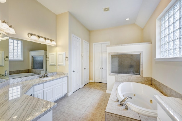 bathroom featuring tile patterned floors, vanity, a relaxing tiled tub, and vaulted ceiling