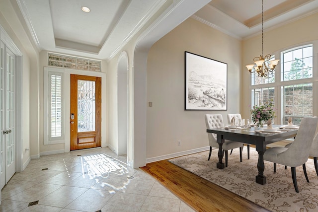 entrance foyer featuring a raised ceiling, ornamental molding, light hardwood / wood-style floors, and an inviting chandelier