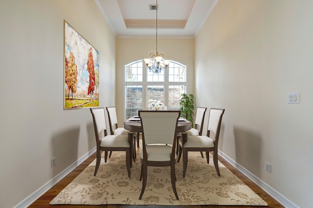 dining room featuring hardwood / wood-style floors, an inviting chandelier, ornamental molding, and a tray ceiling