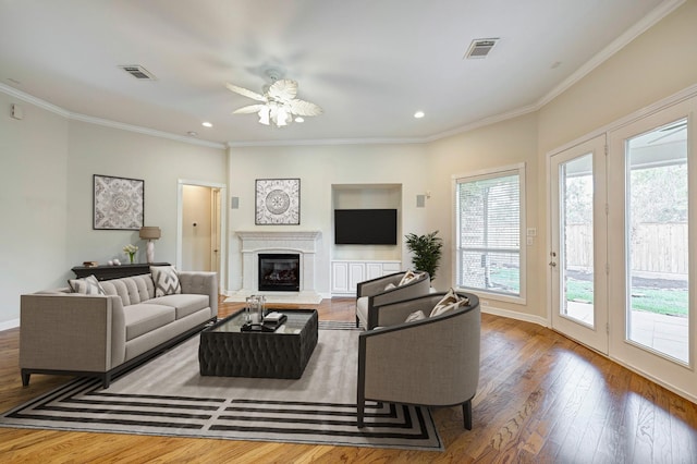 living room featuring ceiling fan, wood-type flooring, and ornamental molding