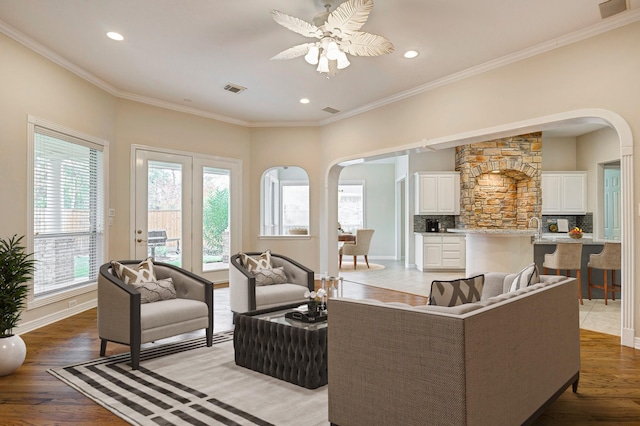 living room featuring ceiling fan, wood-type flooring, and crown molding