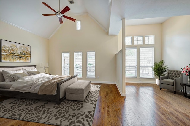 bedroom with wood-type flooring, high vaulted ceiling, ceiling fan, and ornamental molding