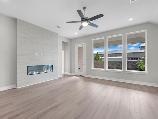 unfurnished living room featuring ceiling fan, a fireplace, and light wood-type flooring