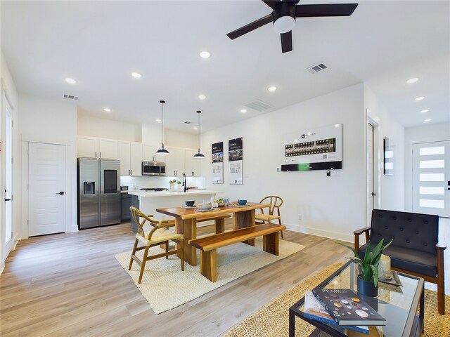 dining space featuring light hardwood / wood-style floors, ceiling fan, and sink