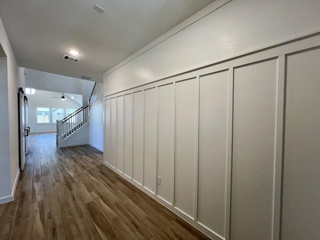 hallway with a barn door and dark wood-type flooring