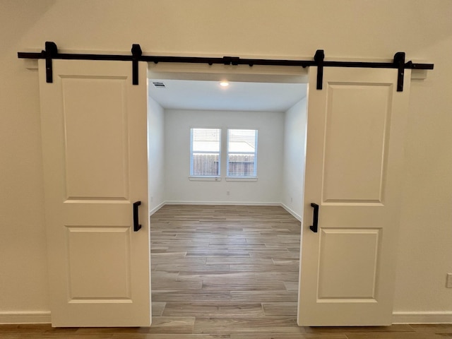 empty room featuring light wood-type flooring and a barn door