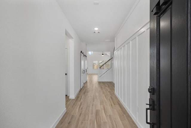 corridor with a barn door and light wood-type flooring