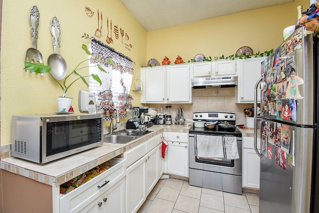 kitchen with white cabinetry, sink, stainless steel appliances, tasteful backsplash, and light tile patterned flooring