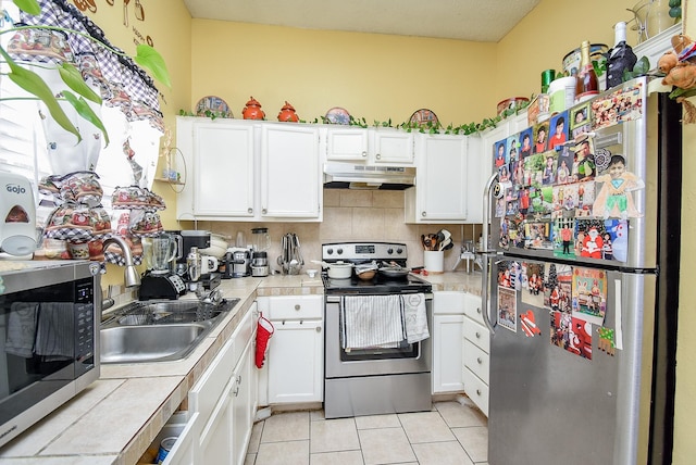 kitchen featuring appliances with stainless steel finishes, tile countertops, white cabinetry, and sink