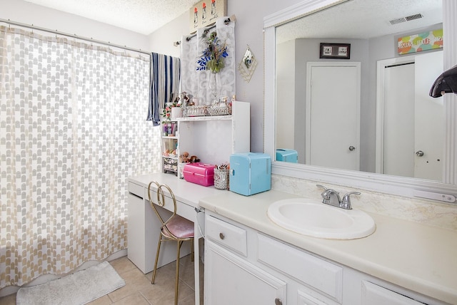 bathroom featuring tile patterned floors, vanity, a textured ceiling, and walk in shower