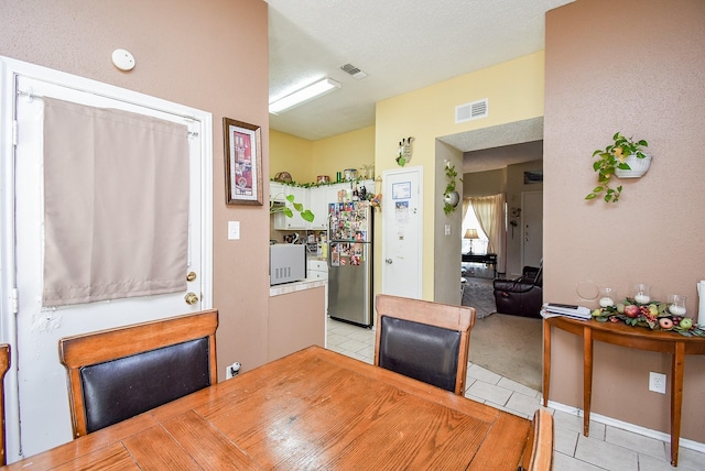 tiled dining area with a textured ceiling