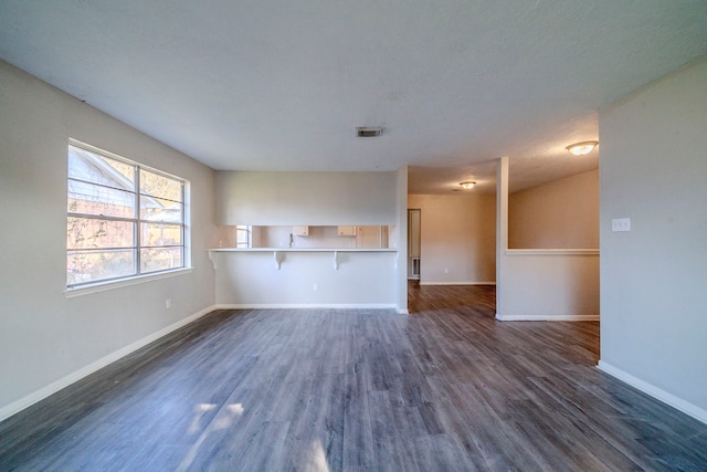 unfurnished living room with dark hardwood / wood-style flooring and a textured ceiling